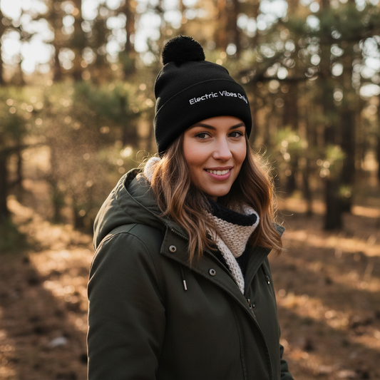 Woman wearing a All Black Pom-Pom Beanie Three-Quarter View standing in the woods.