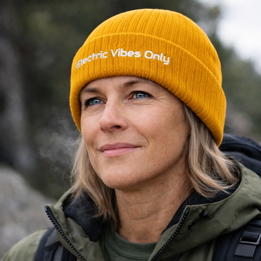 Women wearing mustard cuffed Electric Vibes Only beanie  standing outdoors, close up head shot.